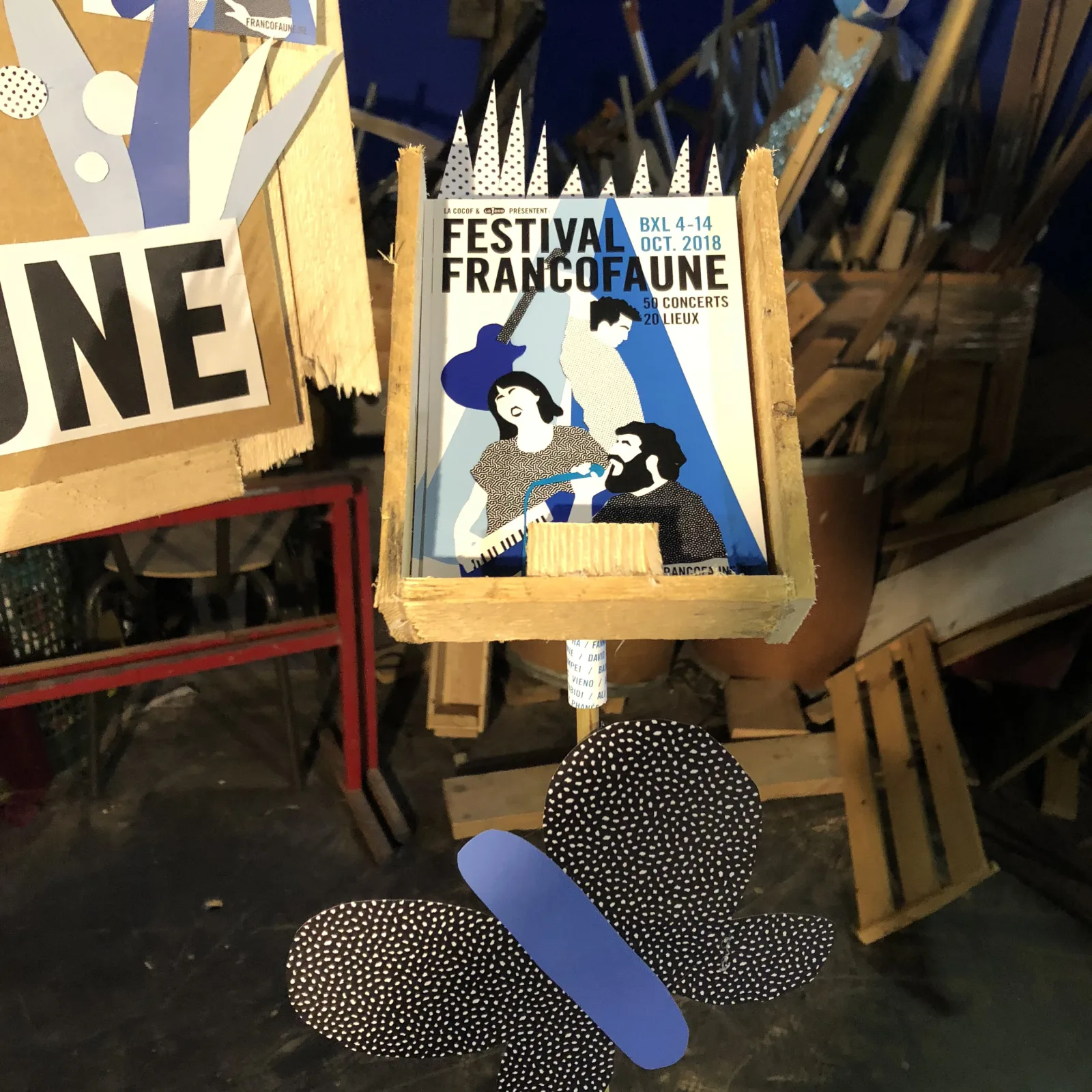 L’installation éclairée en bleu : affiche encadrée et tiges surmontées de pliages