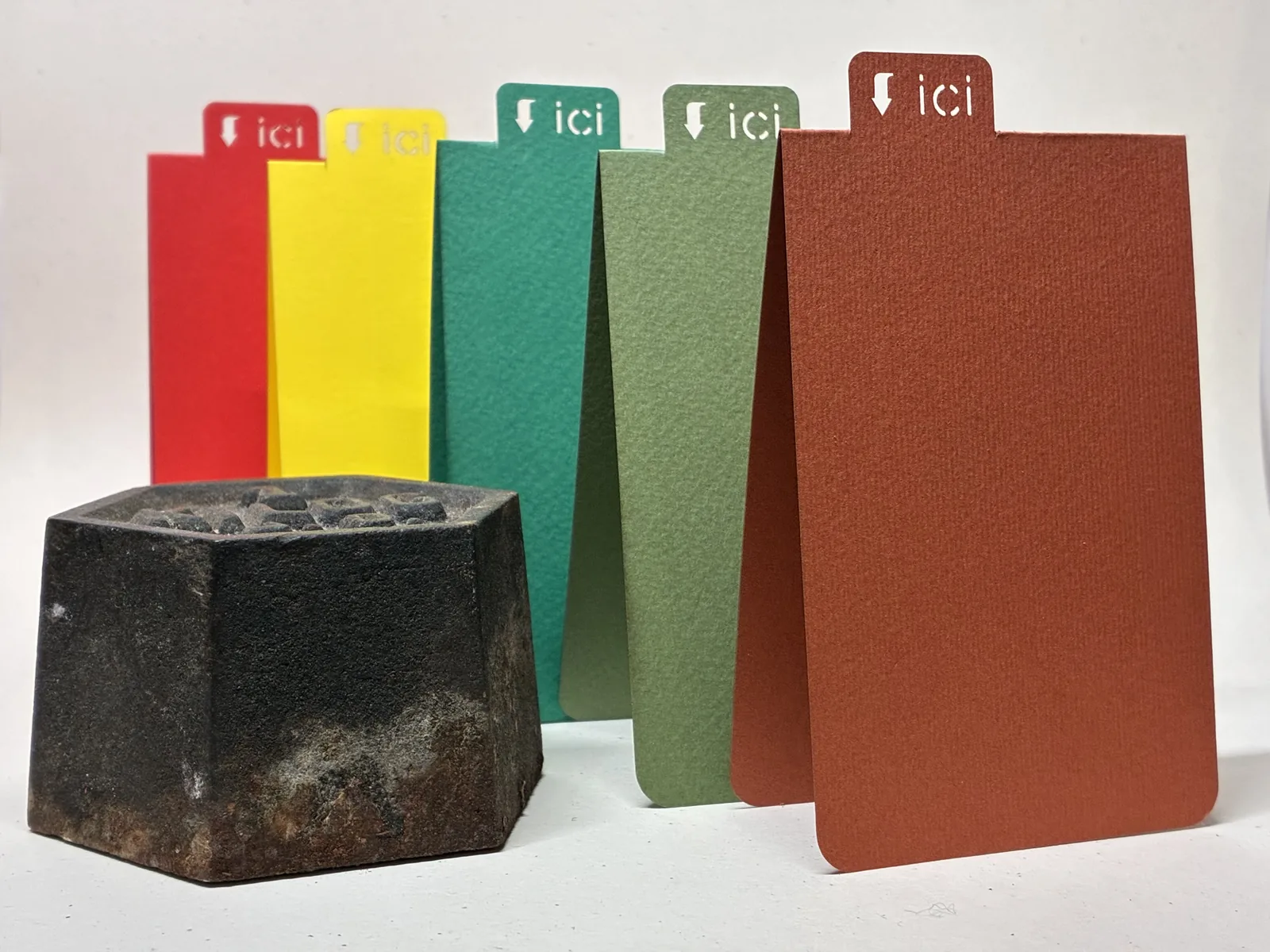 La matrice de découpe, un bloc de métal hexagonal noirci, posée devant la série de couleurs
