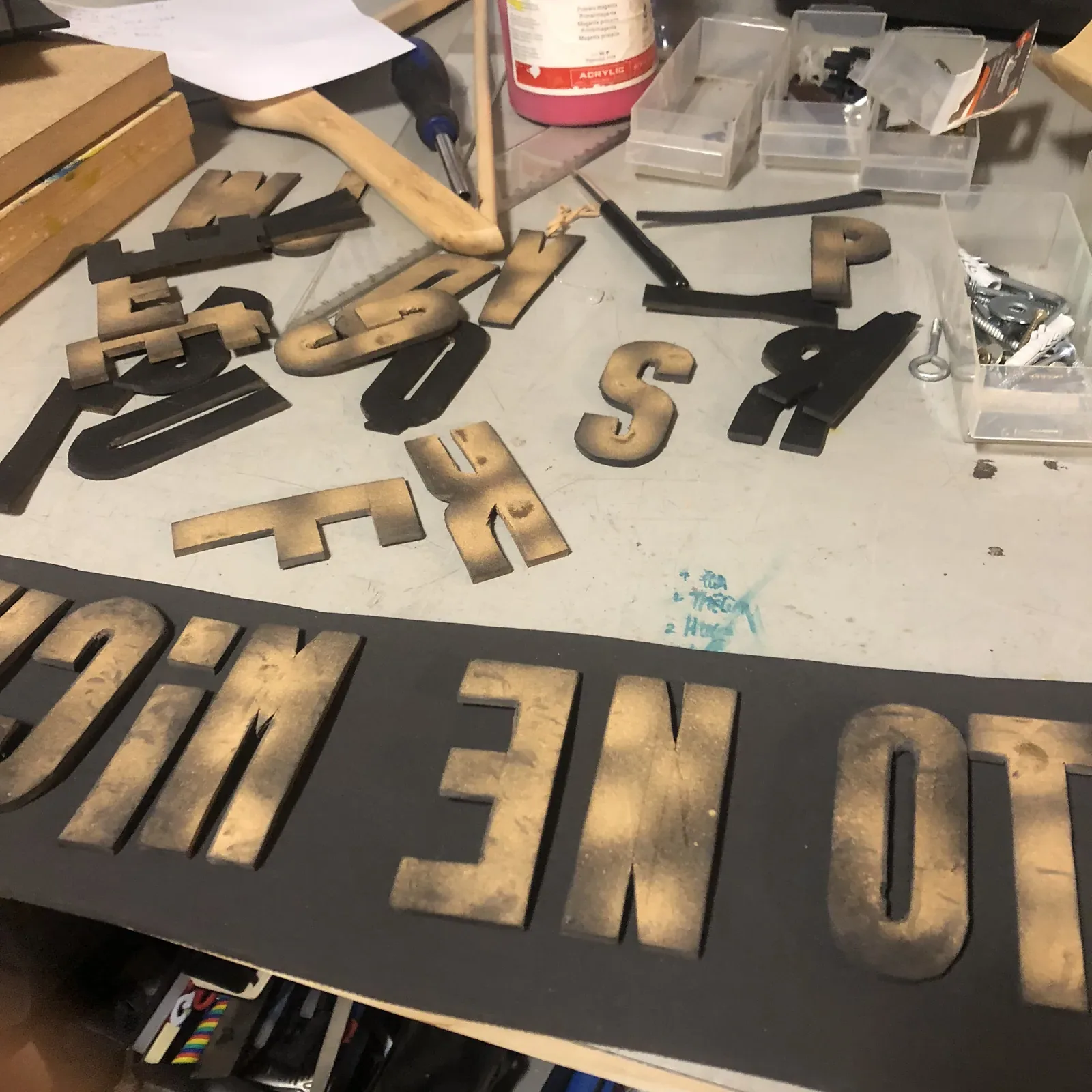 L’atelier de la presse : lettres de bois en vrac, panneaux au pochoir, colle et outils