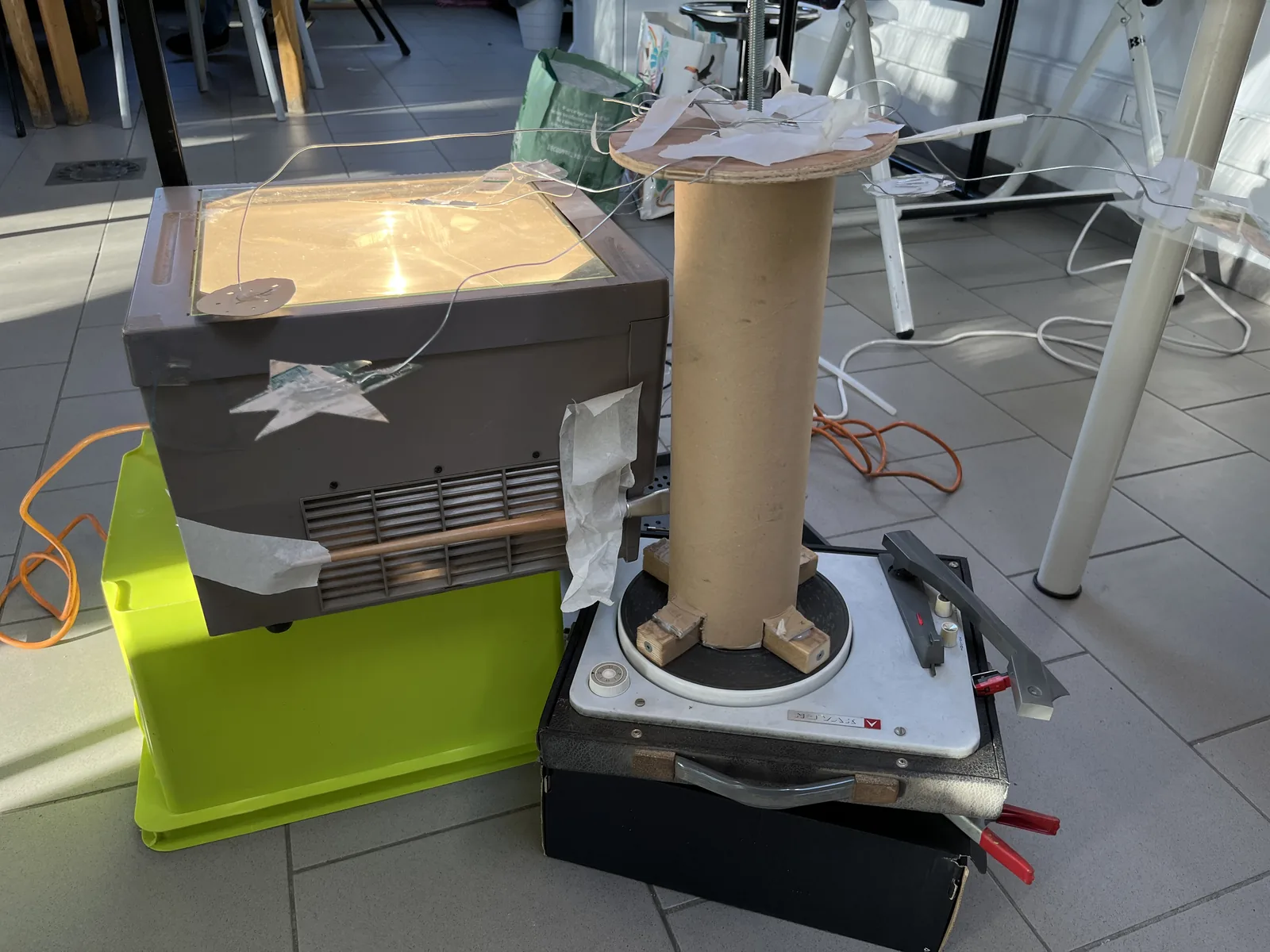 Un rétroprojecteur gréé sur sa caisse, une colonne de carton devant la lentille